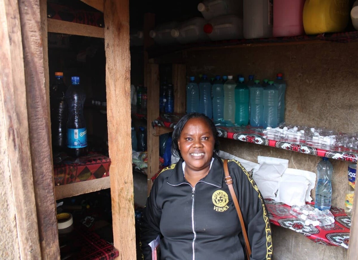 A woman with disabilities stands in her soap-making workshop, smiling.