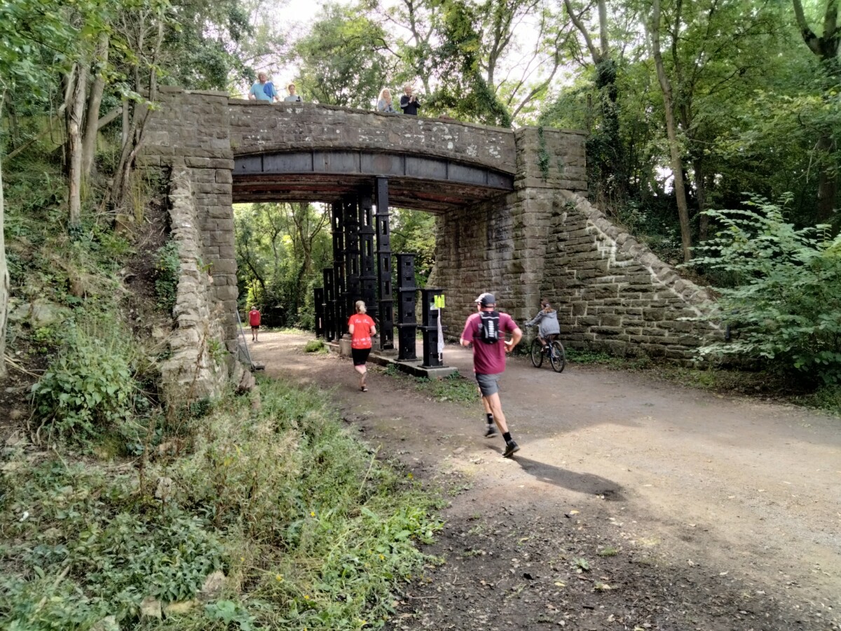 Runners run under a bridge on the Wye Valley Tunnel Run route.